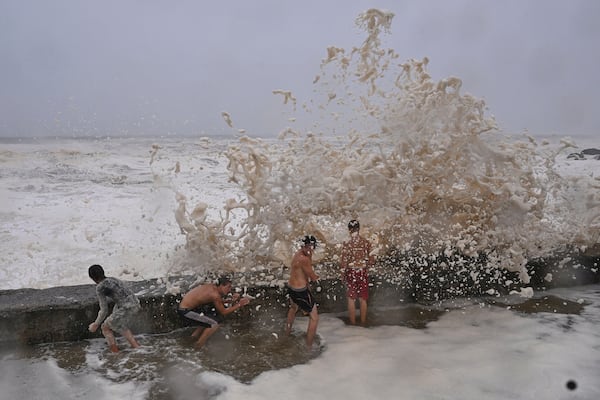 Children take shelter from waves behind a breakwall in the Coolangatta area of Gold Coast, Australia, Friday, March 7, 2025. (Dave Hunt/AAP Image via AP)