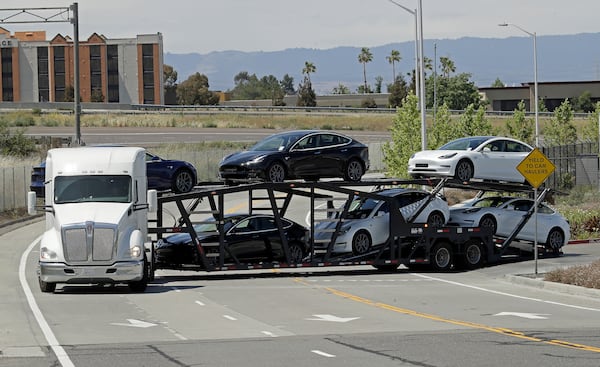 A truck hauling new Tesla vehicles leaves the factory plant  Monday.