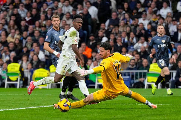 Real Madrid's Vinicius Junior, centre, in action against Rayo's goalkeeper Augusto Batalla during the Spanish La Liga soccer match between Real Madrid and Rayo Vallecano at the Santiago Bernabeu stadium in Madrid, Spain, Sunday, March 9, 2025. (AP Photo/Manu Fernandez)