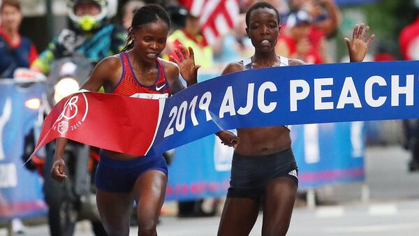 Brigid Kosgei (left) just beats Agnes Tirop (right) to win the 50th AJC Peachtree Road Race with an unofficial record time of 30:22 on Thursday, July 4, 2019, in Atlanta.  Curtis Compton/ccompton@ajc.com