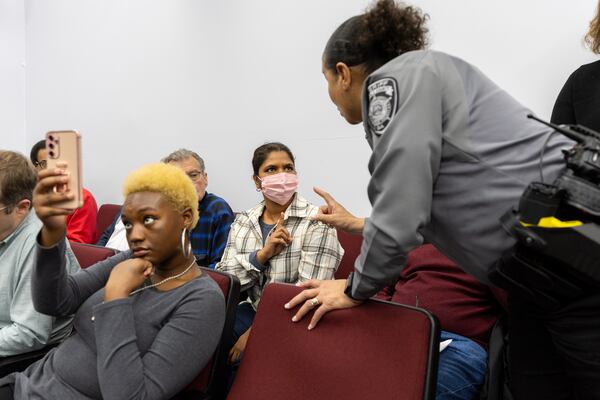 Satya Yatti (center) speaks to a deputy after an outburst in support of public comment at the Rockdale County Board of Commissioners meeting.