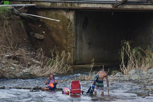 A couple bathes in the Gurabo River in the aftermath of Hurricane Maria in Las Piedras, Puerto Rico, Monday, Oct. 2, 2017. Power is still cut off on most of the island, schools and many businesses are closed and much of the countryside is struggling to find fresh water and food. (AP Photo/Carlos Giusti)