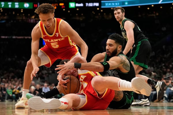 Atlanta Hawks' Garrison Mathews, bottom left, battles Boston Celtics' Jaylen Brown, front right, for the ball as Hawks' Dyson Daniels (5) moves in during the first half of an NBA basketball game, Saturday, Jan. 18, 2025, in Boston. (AP Photo/Robert F. Bukaty)