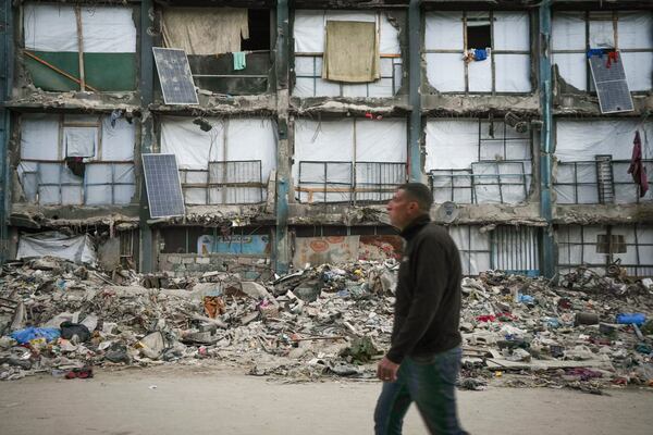 A man walks past a house that remains partly standing, but with sheets serving as makeshift walls and solar panels partly working, in an area largely destroyed by the Israeli army's air and ground offensive in Gaza City, Wednesday, Feb. 5, 2025. (AP Photo/Abdel Kareem Hana)