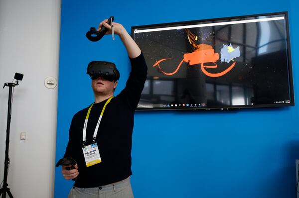 Matthew Taylor paints in 3D virtual reality at the Intel booth using HTC Vive virtual reality goggles at CES International, Wednesday, Jan. 6, 2016, in Las Vegas. (AP Photo/John Locher)