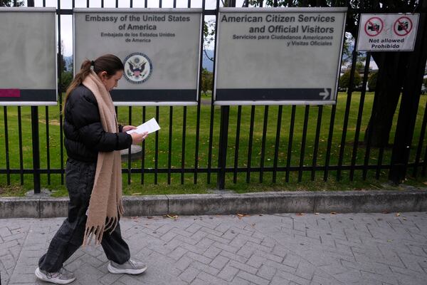 A woman reads a notification about canceling her visa appointment due to Colombian President Gustavo Petro's refusal to accept repatriation flights for Colombian citizens from the United States, outside the U.S. embassy in Bogota, Colombia, Monday, Jan. 27, 2025. (AP Photo/Fernando Vergara)