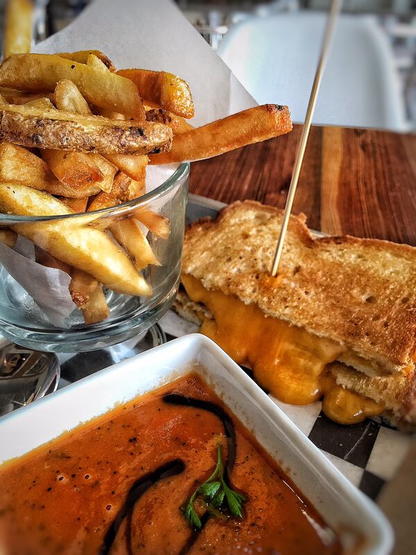 A "classic" grilled cheese sandwich (cheddar and hearty white bread) is served with a cup of tomato basil soup at the Grilled Cheese Gallery in the historic Northwood district of West Palm Beach. (Liz Balmaseda/ Palm Beach Post)