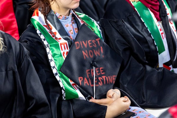 A graduate holds a graduation cap with a pro-Palestinian message in Sanford Stadium during the University of Georgia spring commencement in Athens on Friday, May 10, 2024. (Arvin Temkar / AJC)