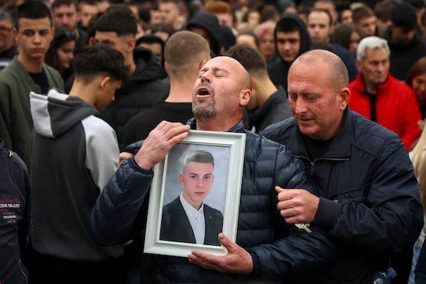 A man cries holding a photograph of victim of a massive nightclub fire during a vigil joined by hundreds in the town of Kocani, North Macedonia, Monday, March 17, 2025, (AP Photo/Armin Durgut)