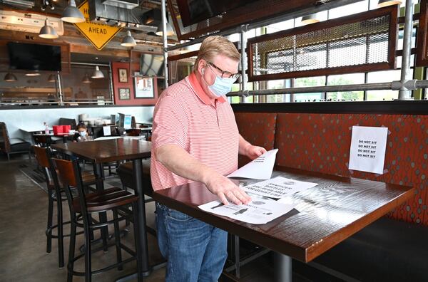 Owner Harry Decker sorts through signs on Saturday, April 25, 2020, for social distancing efforts as restaurant staff prepare to reopen the restaurant at Bad Daddy’s Burger Bar in Decatur. Gov. Brian Kemp announced that movie theaters and restaurant dining rooms can reopen Monday, April 27, following guidelines. (Hyosub Shin / Hyosub.Shin@ajc.com).