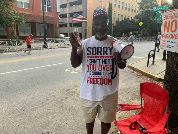 Matthew Hutcherson, 66, of Riverdale, playfully teased the runners as they neared the finish line Saturday: “You are going to slow! Speed it up!” he announced through a megaphone. (Photo: Jeremy Redmon/AJC)