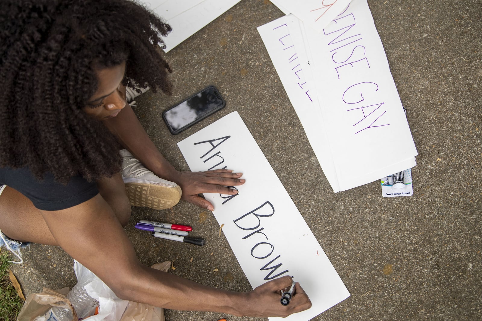 A participant in the "Say Her Name" rally and march Sunday writes down the names of African American women harmed by police. (ALYSSA POINTER / ALYSSA.POINTER@AJC.COM)