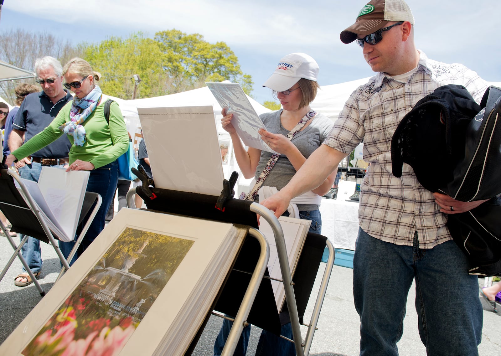 Kyle Godfrey (right), his wife Laurean and Linda and Allen Marchetti look at the photographs for sale in Winthrope Hiers' booth during the Alpharetta Arts Streetfest Saturday, April 13, 2013. The streets of historic downtown Alpharetta were closed as nearly 100 artists, musicians and performers from throughout the U.S. were showcased during the weekend long event.