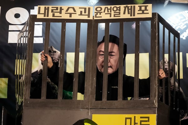 A participant wearing a mask of South Korean President Yoon Suk Yeol performs during a rally to demand his impeachment outside the National Assembly in Seoul, South Korea, Wednesday, Dec. 11, 2024. The signs read "Arrest the rebellion leader Yoon Suk Yeol." (AP Photo/Ahn Young-joon)