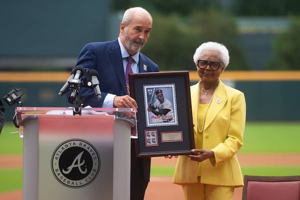 Thomas J. Marshall, general counsel and executive vice president of the United States Postal Service, offers a framed Hank Aaron stamp sample to his wife, Billye, at the USPS ceremony marking the stamp's sale debut at Truist Park in Atlanta on Wednesday, July 31, 2024.  (Ziyu Julian Zhu / AJC)