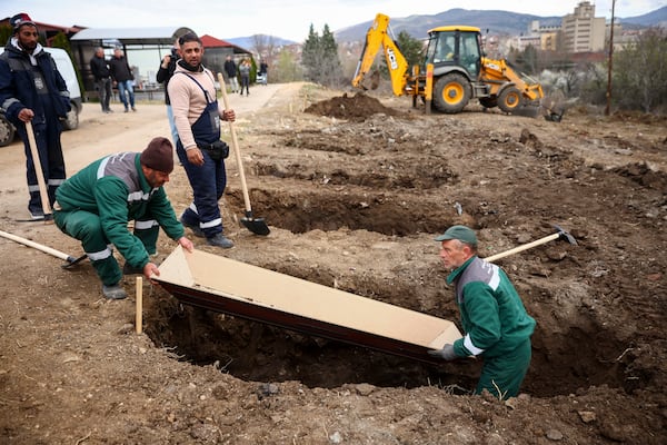 Municipal workers use an empty coffin to measure the graves they are digging for the victims of a massive nightclub fire, in the town of Kocani, North Macedonia, Tuesday, March 18, 2025. (AP Photo/Armin Durgut)