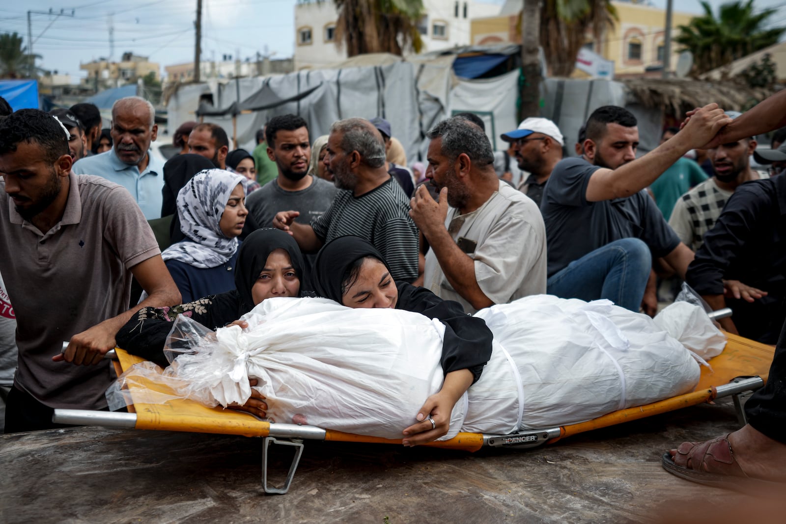 FILE - Palestinian women mourn a relative killed in the Israeli bombardment of the Gaza Strip, at a hospital in Deir al-Balah, Thursday, Aug. 22, 2024. (AP Photo/Abdel Kareem Hana, File)