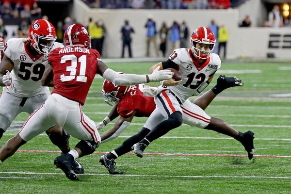 Bulldogs quarterback Stetson Bennett (13) eludes the tackle by Alabama Crimson Tide linebacker Will Anderson Jr. (31) and linebacker Christian Harris (8).   Curtis Compton / Curtis.Compton@ajc.com 