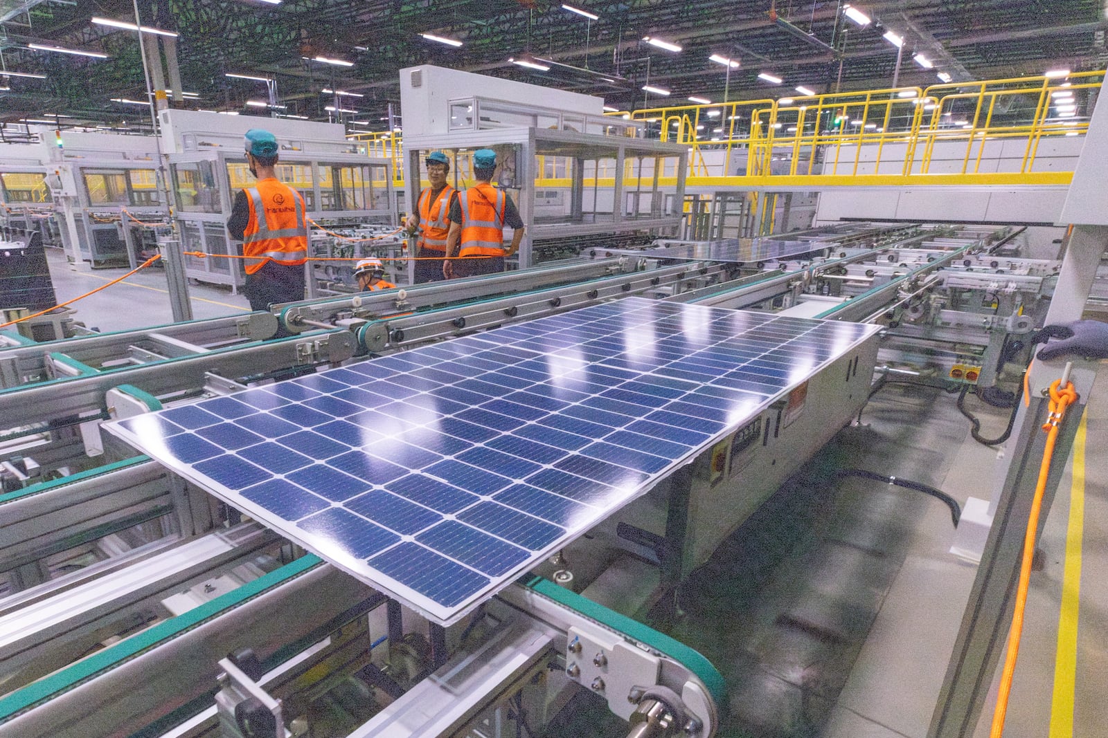 Workers keep an eye on the solar panels as they move through the automated assembly line at the Qcells module production facility in Cartersville on April 2.  Steve Schaefer/AJC 2024