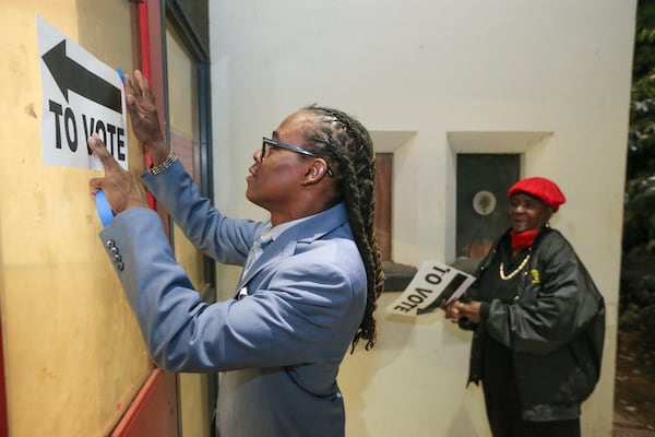 Poll workers DeCarlos Bennett (left) and Catherine Gray (right) put up signage on Tuesday, Nov. 8, 2016 at Henry W. Grady High School. JOHN SPINK /JSPINK@AJC.COM