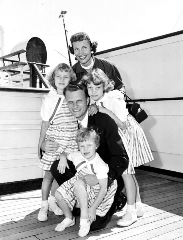 FILE - In this July 7, 1954 file photo,  Evangelist Billy Graham poses with his his wife, Ruth, and their three daughters on the Queen Mary following his arrival in New York.   Graham, who transformed American religious life through his preaching and activism, becoming a counselor to presidents and the most widely heard Christian evangelist in history, has died. Spokesman Mark DeMoss says Graham, who long suffered from cancer, pneumonia and other ailments, died at his home in North Carolina on Wednesday, Feb. 21, 2018. He was 99. (AP Photo)