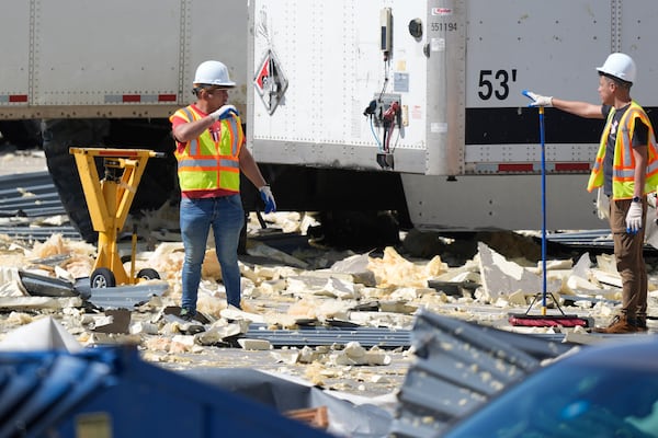 Workers talk while cleaning up debris from a damaged warehouse after storms moved through Tuesday, March 4, 2025, in Lewisville, Texas. (AP Photo/LM Otero)