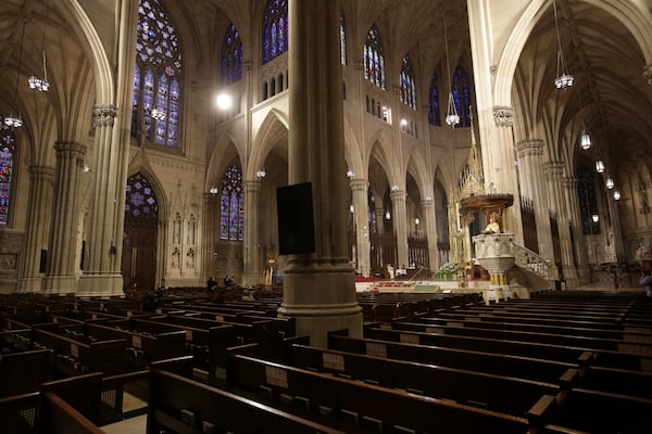 Archbishop Timothy Dolan, right, delivers his homily over mostly empty pews as he leads an Easter Mass at St. Patrick's Cathedral in New York. Due to coronavirus concerns, no congregants were allowed to attend the Mass, which was broadcast live on local TV. The New York archdiocese received at least four large Paycheck Protection Program loans, one worth at least $5 million.