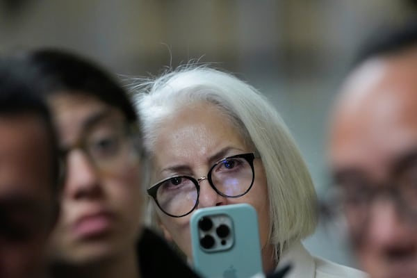 Mahnaz Tayarani, center, mother of Nima Momeni, who is charged with murder in Cash App founder Bob Lee's stabbing death, records video as defense attorney Saam Zangeneh speaks to reporters after exiting the courtroom at the Hall of Justice for Momeni's murder trial Tuesday, Dec. 3, 2024, in San Francisco. (AP Photo/Godofredo A. Vásquez)