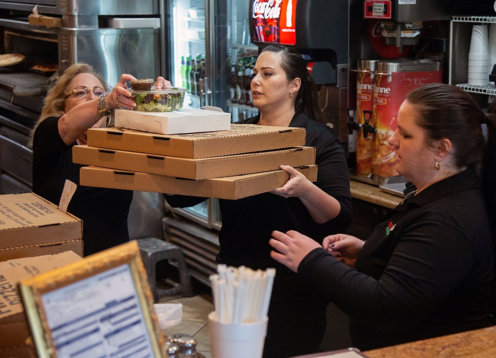 Joanna Fini (C) gets an order ready to go out during the Friday night rush at Fini’s Pizzeria in Lawrenceville. STEVE SCHAEFER / SPECIAL TO THE AJC