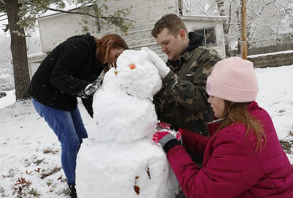 Andrew Davis and his sisters Brook, left, and Kyla make the first snowman of the season along Center Street in Springfield Tuesday. Bill Lackey/Staff