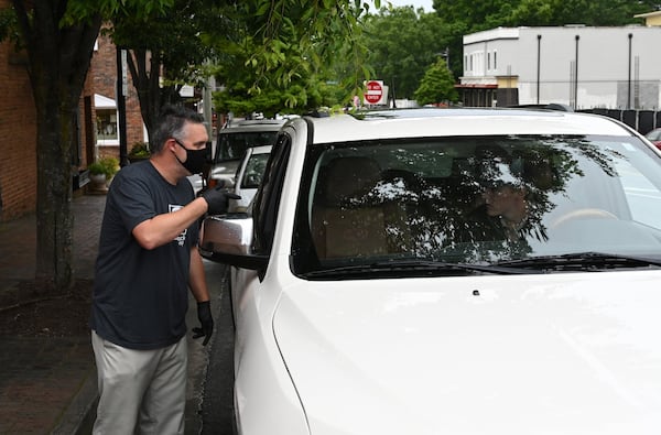 Connor Herrington makes a curbside delivery of LP albums to Duncan Murphy in his car outside Comeback Vinyl, a new and used independent record store in downtown Alpharetta, on Friday, May 8, 2020. Retail has suffered during the pandemic, and record shops are no exception. Some posted GoFundMe campaigns to help them stay afloat and pay employees, some offered mail order and curbside pickup and now a few are slowly reopening their doors to customers. (Hyosub Shin / Hyosub.Shin@ajc.com)