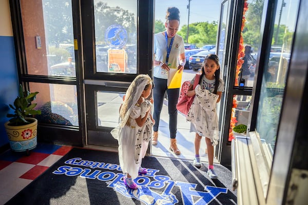 Attendance Clerk Katrice Grant follows siblings Melanie Pacheco, 8, right and Marilynn Pacheco, 5, as they arrive for school, Tuesday, Oct. 1, 2024, at Algodones Elementary School in Algodones, N.M. (AP Photo/Roberto E. Rosales)