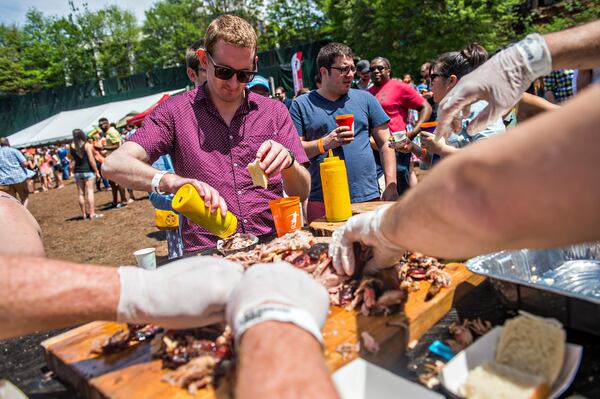 Robert Christopher (center) pours some sauce on his barbeque during the Hogs & Hops Festival at The Masquerade in Atlanta on Saturday, April 11, 2015. The annual festival featured beer and barbeque as well as live music and games. JONATHAN PHILLIPS / SPECIAL