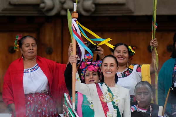 Newly inaugurated Mexican President Claudia Sheinbaum smiles as she holds the staff of office during a rally in the Zócalo, Mexico City's main square, Oct. 1, 2024. (AP Photo/Eduardo Verdugo, File)