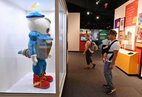 Jason Salgato of Atlanta and his 3-month-old son Cole view Izzy, the 1996 Olympic mascot, displayed at the Atlanta History Center on Tuesday, July 20, 2021. The museum has an ongoing exhibit about the 1996 Olympic Games in Atlanta. (Hyosub Shin / Hyosub.Shin@ajc.com)