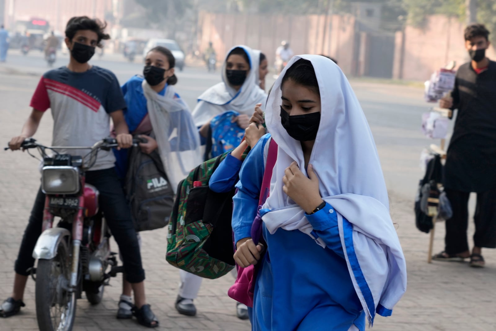 Students wear mask to protect themselves from poor air quality due to increasing smog in the city as they arrive at their school, in Lahore, Pakistan, Monday, Nov. 4, 2024. (AP Photo/K.M. Chaudary)