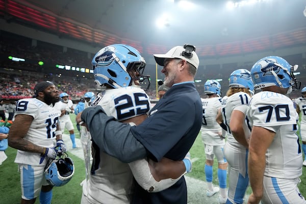 Toronto Argonauts head coach Ryan Dinwiddie, center right, celebrates with teammate Ka'Deem Carey (25) during the second half of a CFL football game at the 111th Grey Cup against the Winnipeg Blue Bombers, in Vancouver, British Columbia, Sunday, Nov. 17, 2024. (Nathan Denette/The Canadian Press via AP)