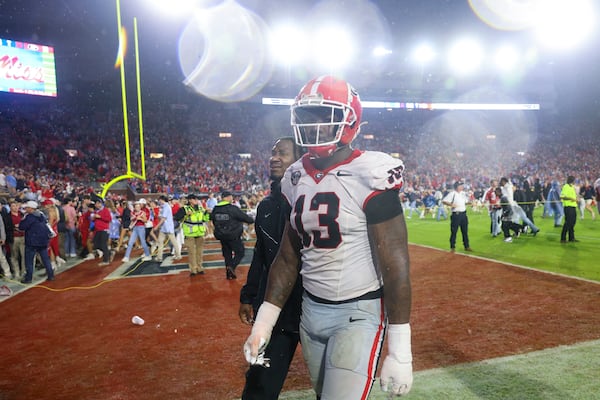 Georgia defensive lineman Mykel Williams (13) is escorted off of the field as Mississippi fans storm the field after Georgia’s loss to Mississippi at Vaught Hemingway Stadium, Saturday, November 9, 2024, in Oxford, Ms. Mississippi won 28-10. (Jason Getz / AJC)
