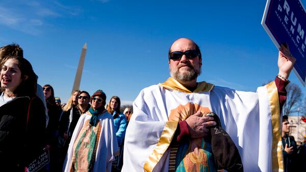 FILE - In this Friday, Jan. 19, 2018 file photo, Brother Tomasio Venditti of Steubenville, Ohio, right, holds a Trump-Pence campaign sign as he and Lis Kelly of Notre Dame, Ind., background, wear white gowns depicting the Lady of Guadalupe during an anti-abortion rally on the National Mall in Washington during the annual March for Life. The annual march to protests the Supreme Court's landmark 1973 decision that declared a constitutional right to abortion.