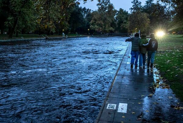 The Baer family, Larry, from left, Tiffany and their daughter Chloe stop to see Big Chico Creek swirling by a swimming area at One Mile Recreation Area, as runoff from Tuesday's rain and melting snow created flooding concerns from an atmospheric river storm that dumped significant precipitation in Chico, Calif., Thursday, Nov. 21, 2024. (Carlos Avila Gonzalez/San Francisco Chronicle via AP)