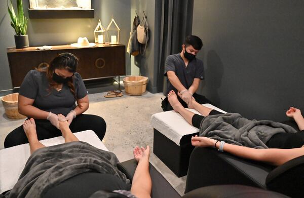 Viviana Torres (left) and Daniel Merida wearing mask and latex glove give customers a massage at Utopia Foot & Shoulder Massage in Atlanta on Thursday, June 11, 2020. PHOTO: Hyosub Shin / Hyosub.Shin@ajc.com