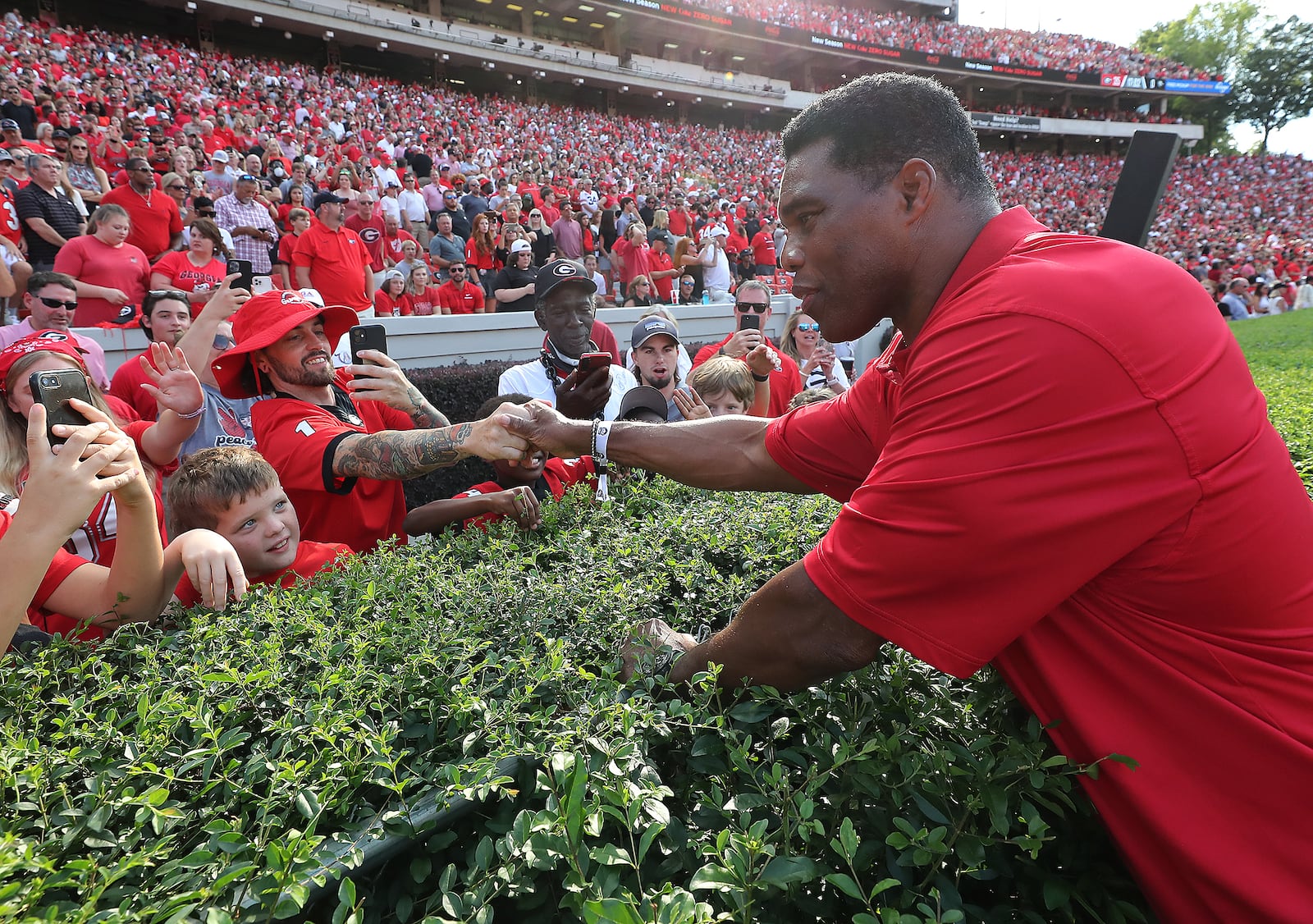 Former University of Georgia running back and U.S. Senate candidate Herschel Walker works the hedges shaking hands with fans before being introduced as part of the 1980 National Championship team during halftime against UAB in a NCAA college football game on Saturday, Sept. 11, 2021, in Athens. (Curtis Compton / Curtis.Compton@ajc.com)