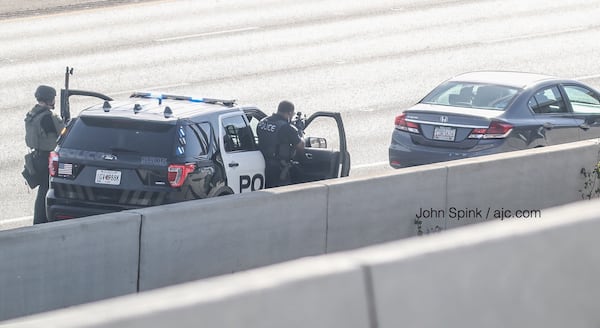 Marietta police officers keep their guns trained on a driver of a gray sedan after pulling the car over to the side of I-75 near Windy Hill Road and I-285. 