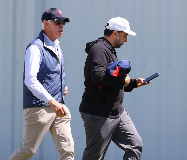 Braves GM Alex Anthopoulos (right) takes a phone call as he is followed by Braves chairman Terry McGuirk on the first day of team practice at spring training on March 14, 2022, in North Port, Fla. (Curtis Compton / Curtis.Compton@ajc.com)