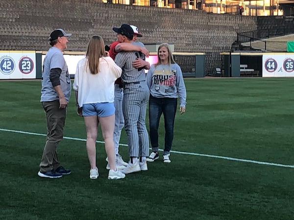 In the company of their parents Mitch and Beth and sister Kyra, Georgia Tech pitcher Jackson Finley (gray uniform) and brother Leighton, a Georgia pitcher, exchange a hug after both competed in the Yellow Jackets' 4-1 win over the Bulldogs on Sunday at Coolray FIeld in Lawrenceville. (AJC photo by Ken Sugiura)