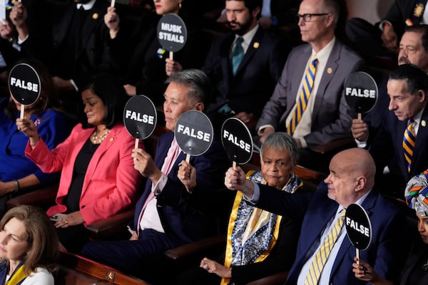 Members of Congress hold up signs as President Donald Trump addresses a joint session of Congress at the Capitol in Washington, Tuesday, March 4, 2025. (AP Photo/J. Scott Applewhite)