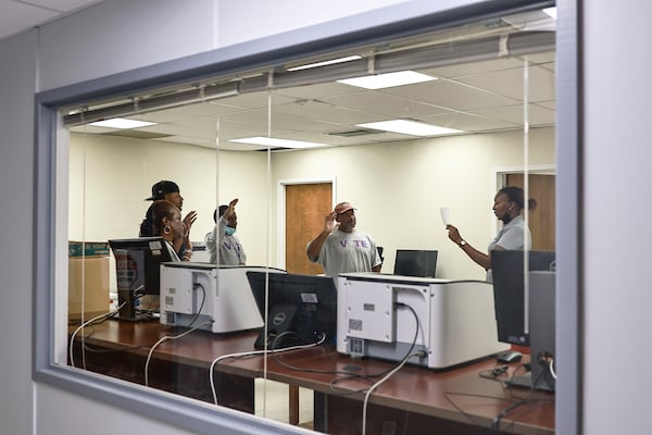 Election technician Brianna Garrett, right, reads "The Oath of Deputy Custodians" to election officials inside the server room at the Clayton County Board of Elections on Wednesday.  (Natrice Miller / natrice.miller@ajc.com)