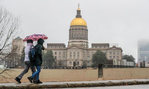 Zulheja Khariy (left) and Farima Khariy (right) walk along Martin Street in downtown Atlanta on Tuesday, Jan. 17, 2023 in a dreary wet day as the Georgia State Capitol looms in the background. (John Spink/The Atlanta Journal-Constitution)

