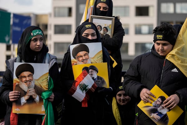 Mourners hold pictures of Lebanon's former Hezbollah leaders, Hassan Nasrallah and Hashem Safieddine, as they gather along a highway to attend their funeral procession in Beirut, Lebanon, Sunday Feb. 23, 2025. (AP Photo/Bilal Hussein)