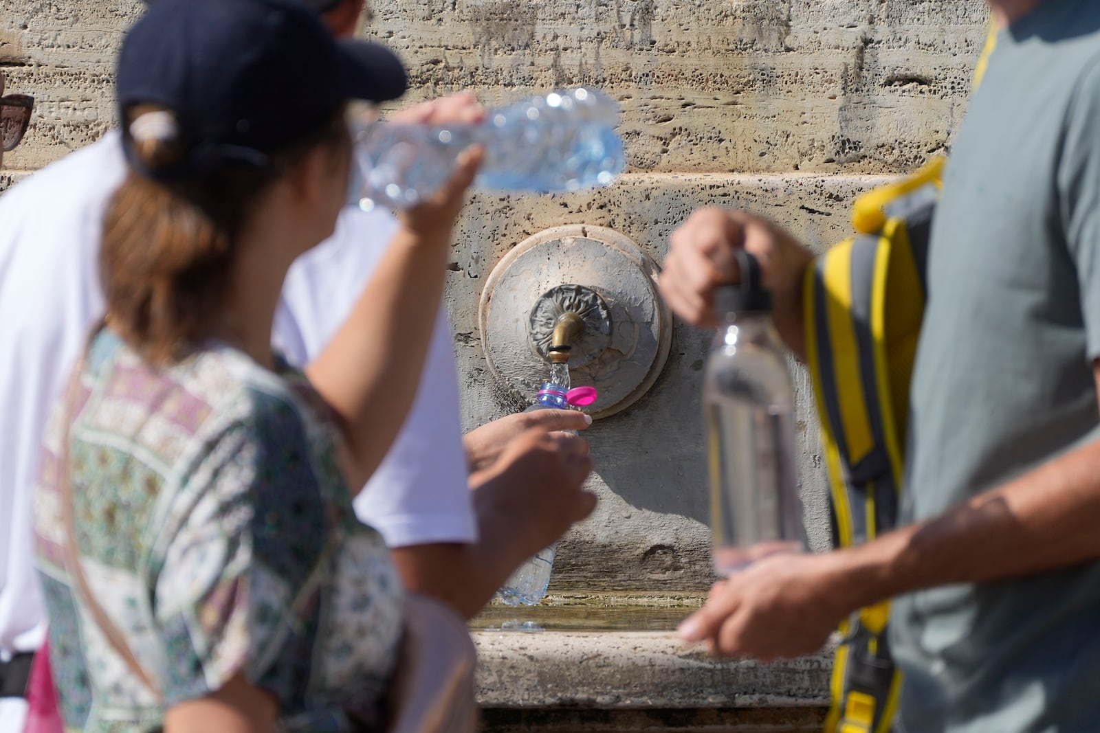 FILE - People queue at a fountain in St. Peter's Square on a hot day at the Vatican, Sunday, Aug. 11, 2024. (AP Photo/Gregorio Borgia, File)